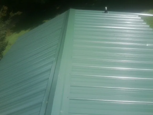 New green metal panels meeting at the ridge of a roof — Flat Roof Repair work by our crew in Atwater