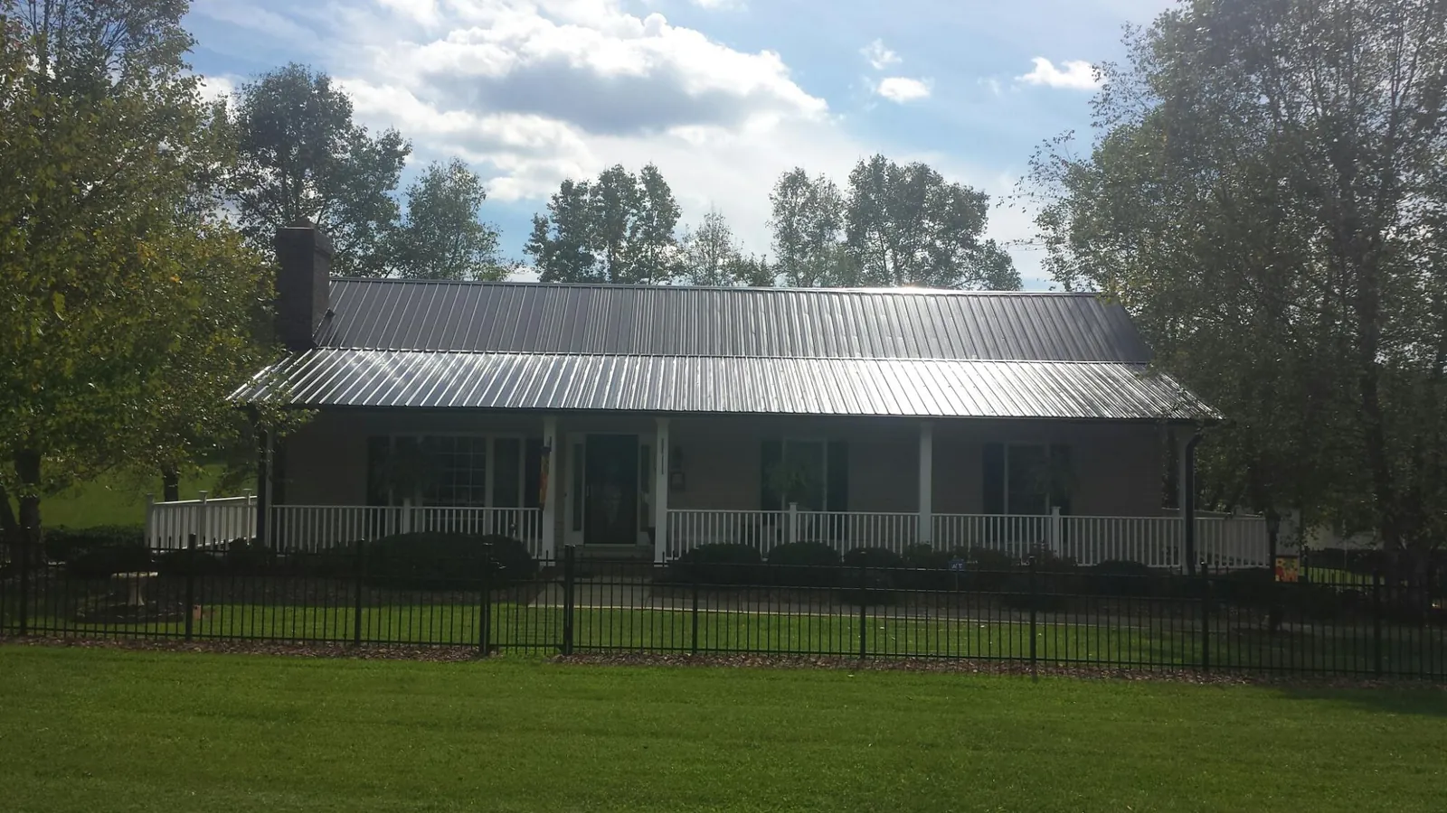 Gray metal roof on a brick ranch with a full width front porch — Gutter Guard Installation work by our crew in Atwater