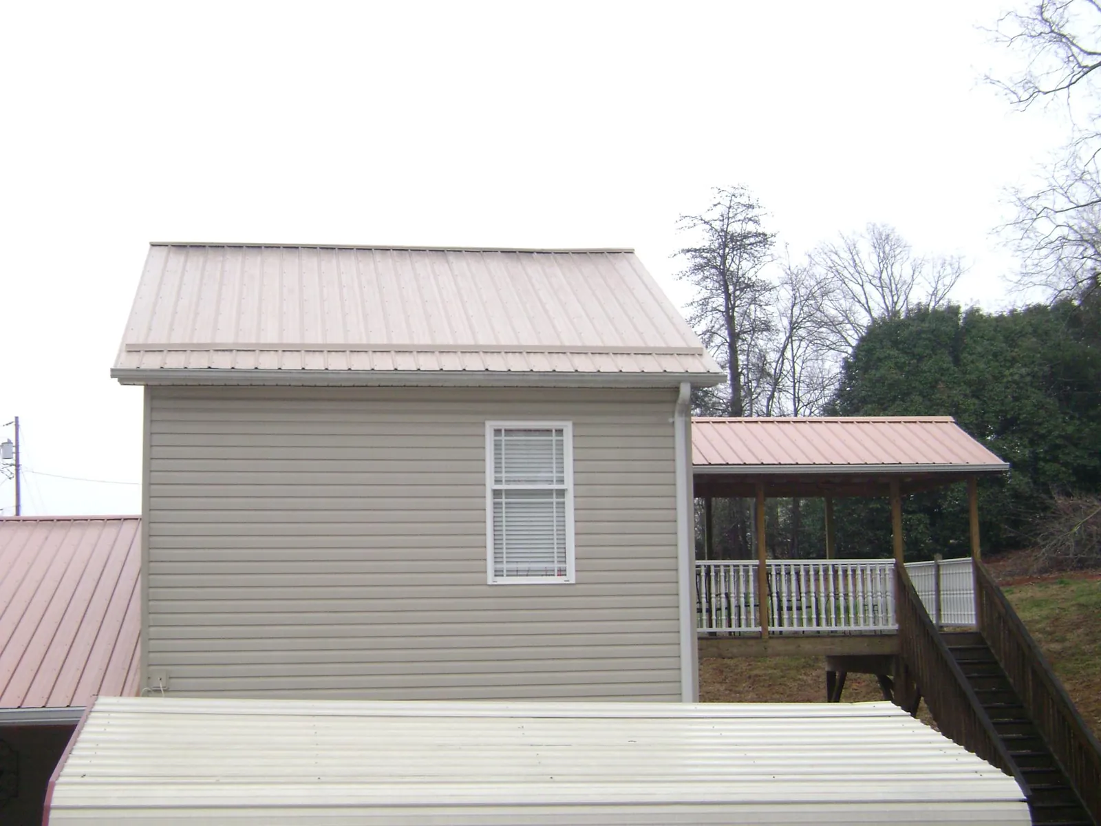 Tan metal roofs on a two story addition and attached porch, from a Roof Replacement job in Atwater